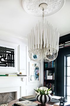 a living room with a chandelier hanging from the ceiling and bookshelves