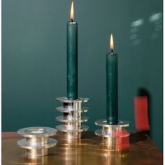 two candles are sitting on top of each other in front of a wall with green walls