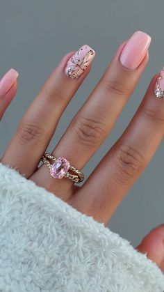 a woman's hand with pink and gold nail polishes on it, holding a ring