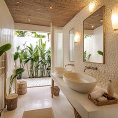 a bathroom with two sinks, mirrors and plants in the shower area on either side of the bathtub