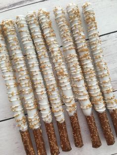 five white and brown sticks with gold sprinkles on them sitting on a wooden table