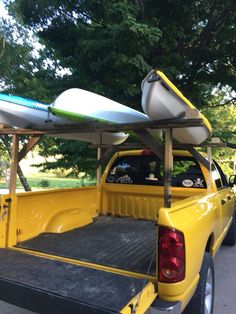 a yellow pick up truck with two surfboards on the back