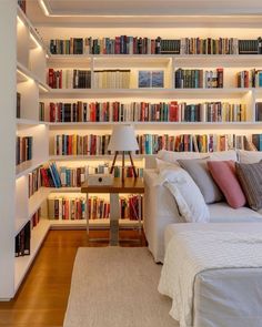 a bed sitting in front of a bookshelf filled with lots of book shelves