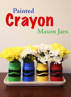 three painted mason jars with flowers in them on a tray that says painted crayon mason jars