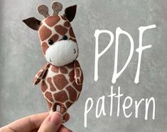 a hand holding a stuffed giraffe in front of a gray background with the words pdf pattern below it