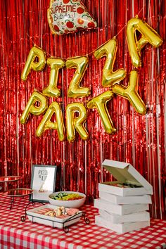 a red and white table topped with pizzas and foil balloons that say pizza party