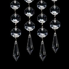 six pairs of clear crystal earrings hanging from hooks on a black background with clippings