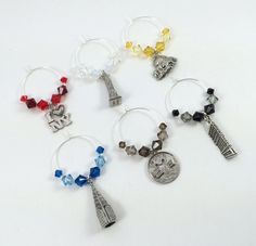 six wine charms with the eiffel tower and other symbols on them, all in different colors