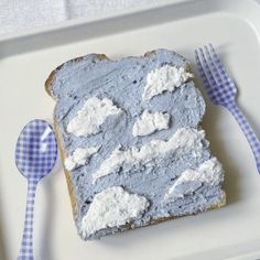 a piece of bread with blue and white frosting on it next to a fork