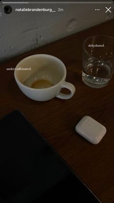 a cup of coffee sitting on top of a wooden table next to a tablet computer