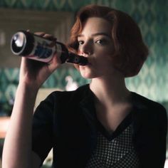 a woman with red hair drinking from a bottle