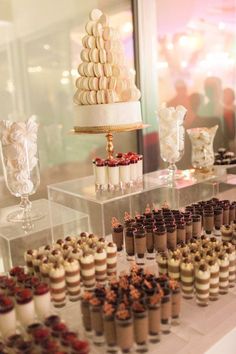 an assortment of desserts on display in front of a glass case at a wedding reception