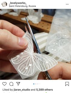 a person cutting fabric with scissors on a table next to some lace and other material