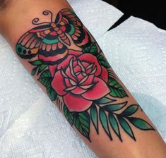 a woman's arm with a butterfly and rose tattoo on it