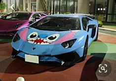 some cars are parked in front of a building with fake teeth on the hoods