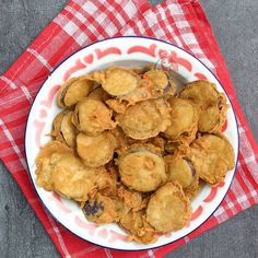 a white bowl filled with fried food on top of a red and white checkered cloth