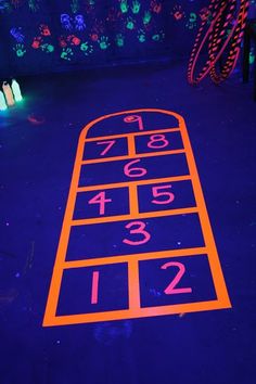 an illuminated parking lot with neon numbers and hand prints on the ground at night time