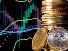 a stack of coins sitting next to a pile of gold and silver coins with candles in the background