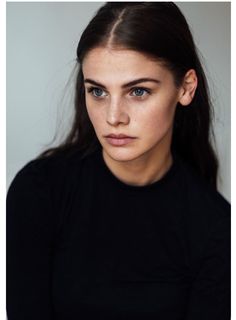 a close up of a person wearing a black shirt and looking at the camera with a serious look on her face