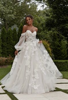 a woman in a white wedding dress standing outside