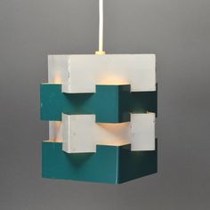 a green and white light fixture hanging from a gray wall next to a grey wall