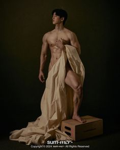 a man standing on top of a wooden box covered in paper toweled material with his shirt draped over him