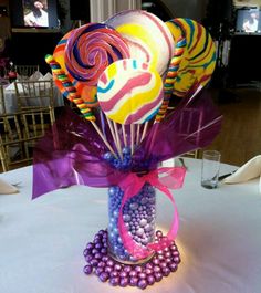 a vase filled with candy and lollipops on top of a white table