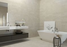 a white bath tub sitting next to a bathroom sink under a large mirror on the wall