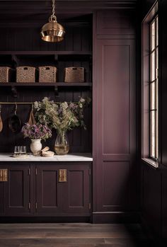 a kitchen with dark wood cabinets and white marble counter tops, brass hanging utensils and vases