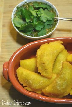 a bowl filled with fried food next to a small bowl full of chopped up vegetables