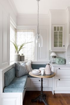 a kitchen with white cabinets and wood flooring next to a breakfast nook table