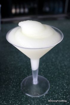 a small glass filled with white liquid on top of a green countertop next to a bottle