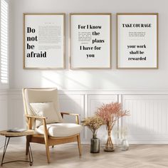 two framed posters on the wall above a chair and vase with flowers in front of it