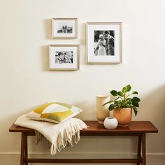 a wooden table topped with pictures next to a potted plant