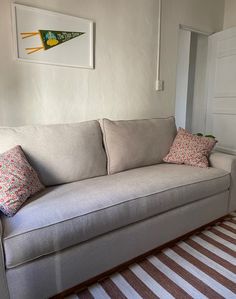 a living room with a white couch and striped rug