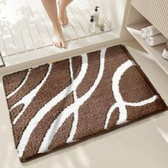 a person standing on a bathroom floor next to a brown rug with white swirls