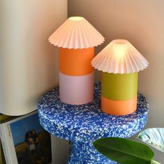 two lamps sitting on top of a blue table next to a white lamphade