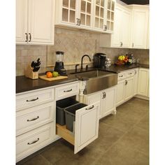 a kitchen with white cabinets and black counter tops, an open dishwasher in the center