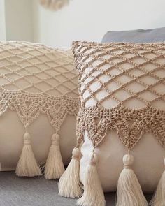 two decorative pillows with tassels on them