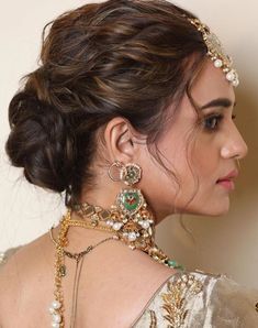 a woman wearing a gold and green necklace with pearls on the back of her head