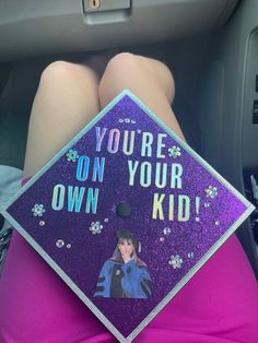 a person wearing a purple graduation cap with the words you're on your own