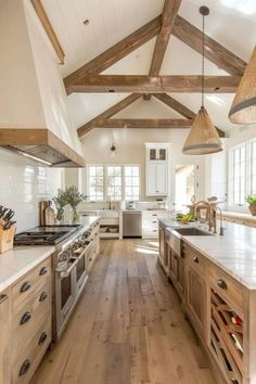 a large kitchen with wooden beams and white counter tops, wood flooring, and stainless steel appliances