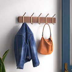 a coat rack with two coats hanging from it and a purse hanging on the wall