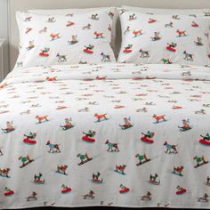 a bed covered in white sheets with snowmen and sleds printed on them