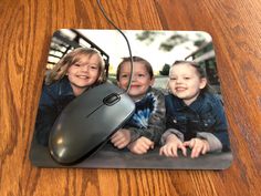 a mouse pad with three children sitting next to each other on a wooden table top