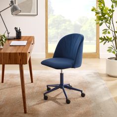 a blue office chair sitting on top of a rug next to a wooden desk with a potted plant