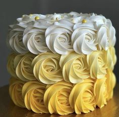 a cake with yellow and white frosting roses on it's side, sitting on a table