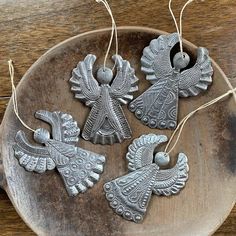 three metal ornaments sitting on top of a wooden plate next to twine strings and thread