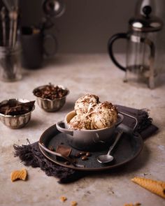 a bowl filled with ice cream next to other bowls and spoons on a table