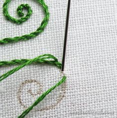 the green thread has been stitched onto the white fabric